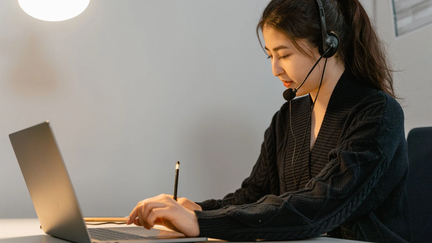 Customer support and sales specialist reviewing client follow-up and CRM records at an organized desk.