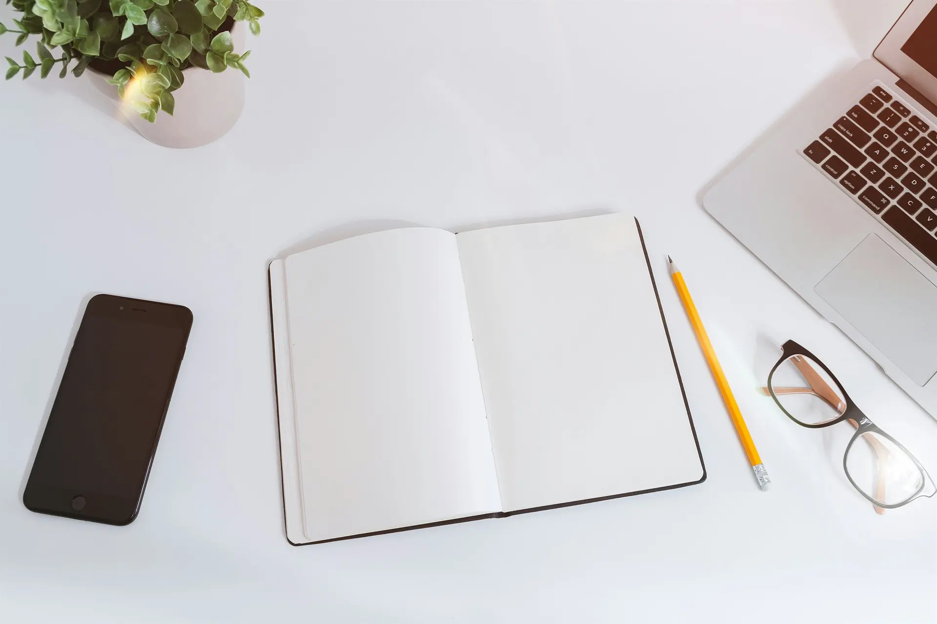 Notebook, laptop and phone arranged for business operations research and executive productivity resources.