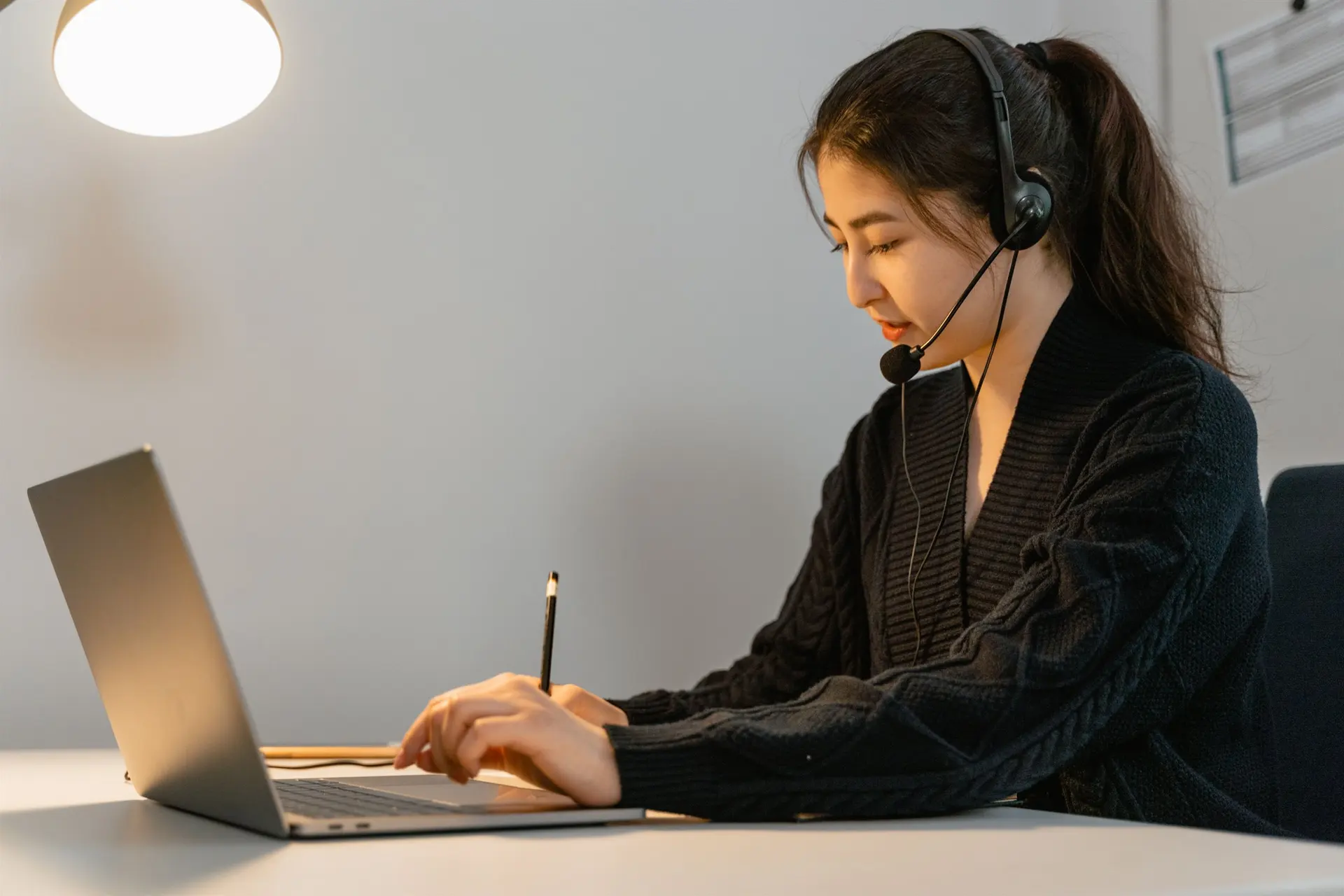 Customer support professional using a headset and laptop to coordinate client enquiries and follow-up.