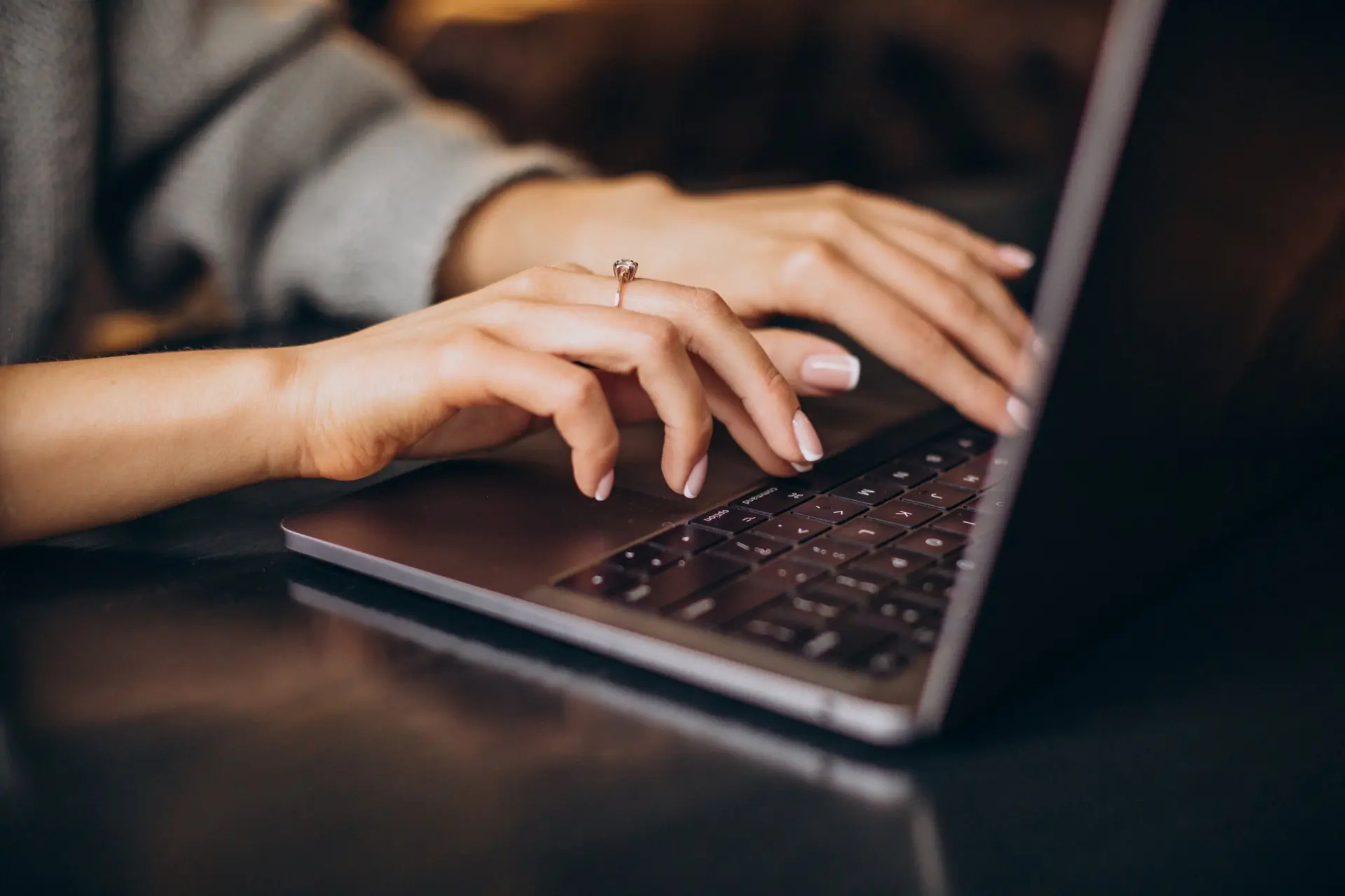 Professional typing at a laptop while reviewing common questions about executive assistance and business operations support.