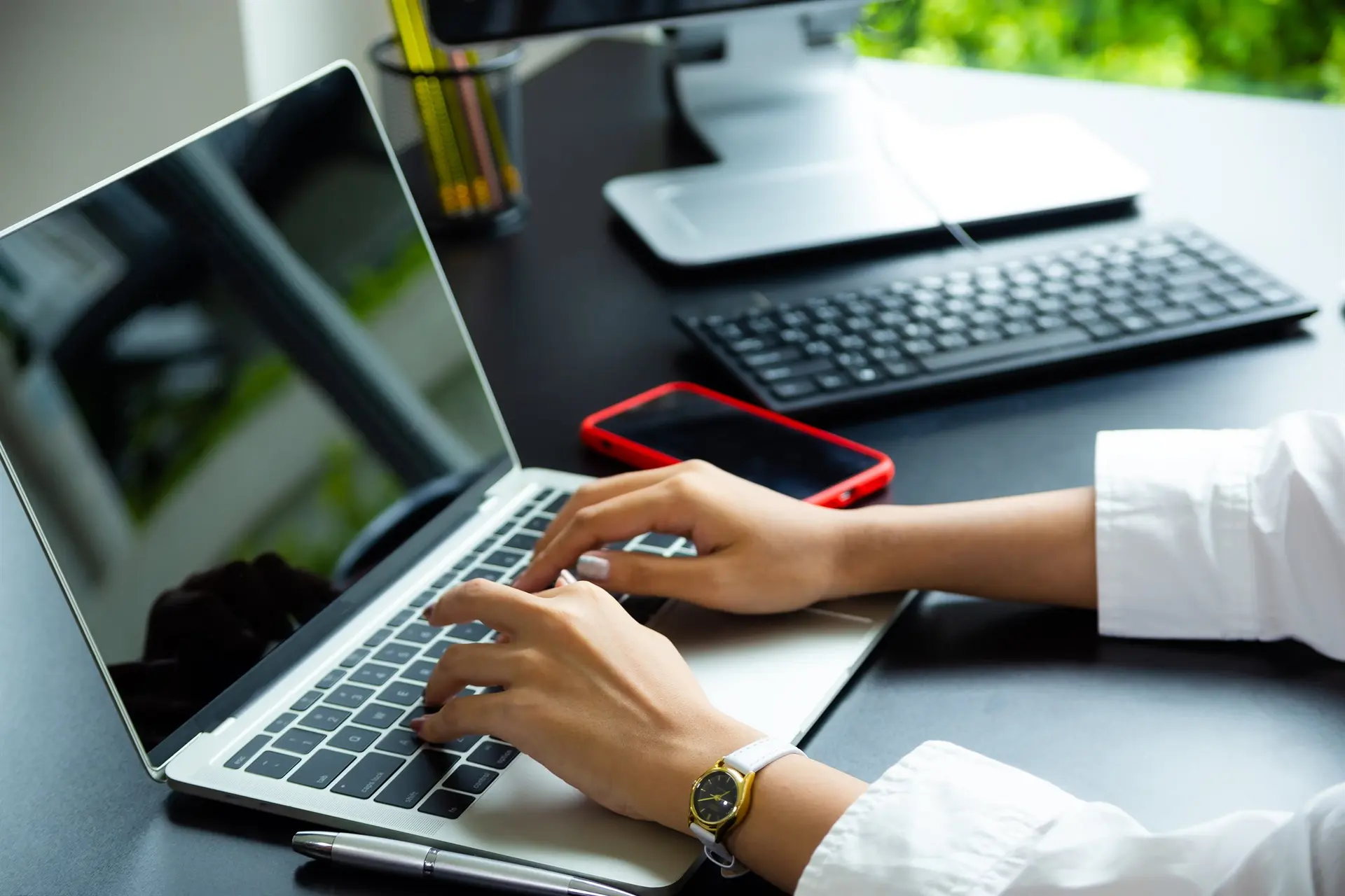 Digital marketing professional working across laptop and desktop screens to coordinate campaigns, content and online visibility.